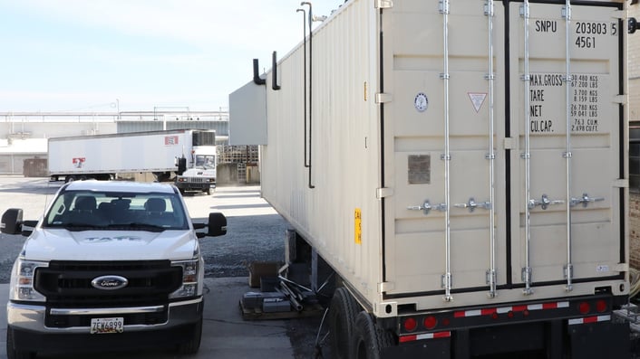 Tate Engineering service truck parked beside a mobile boiler room container during a rental deployment at an industrial facility. Photo shows the temporary boiler unit positioned on-site for emergency or planned steam support.